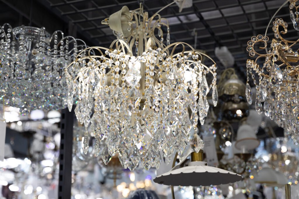 Close-up crystal large chandelier among ceiling lamps in lighting fixtures store